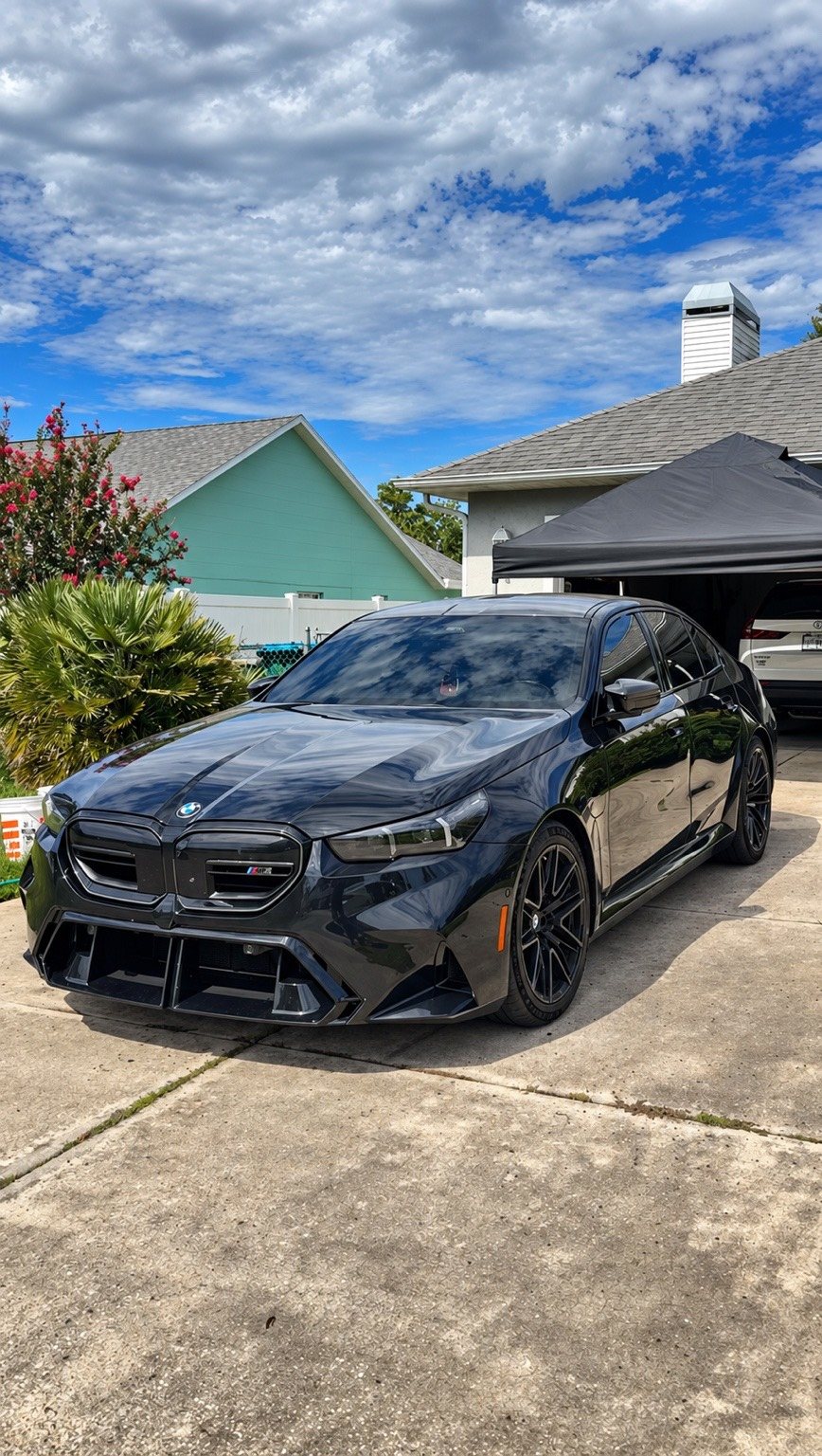 Glossy black BMW M5 in a driveway after an exterior detail